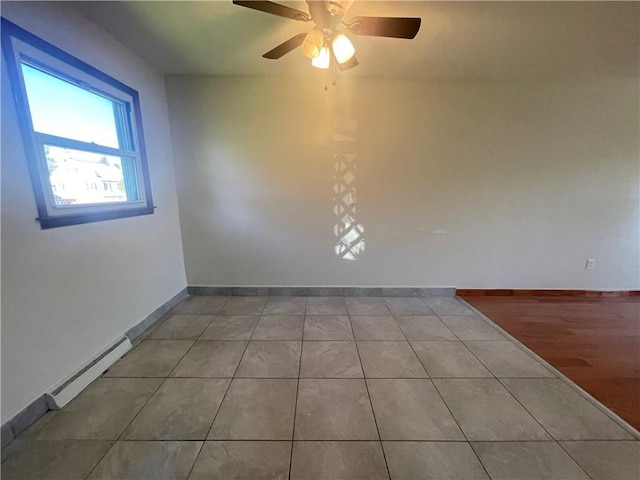 tiled empty room with ceiling fan and a baseboard radiator