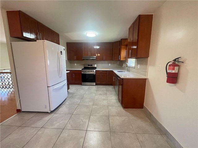 kitchen featuring white refrigerator, stainless steel range oven, sink, and light tile patterned flooring