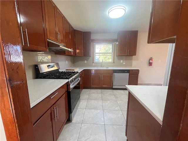 kitchen with light tile patterned flooring, stainless steel appliances, light stone countertops, and sink