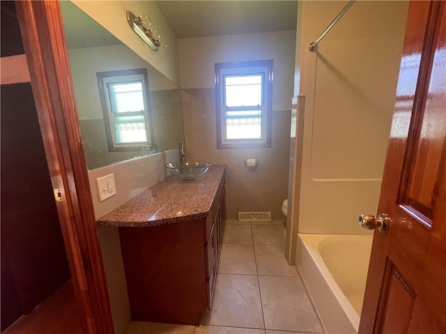 full bathroom with toilet, vanity, tile patterned floors, and a healthy amount of sunlight