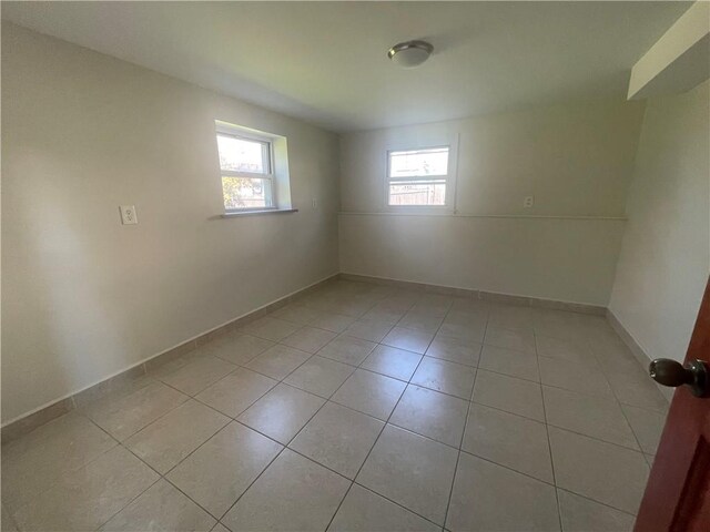 empty room featuring a wealth of natural light and light tile patterned flooring