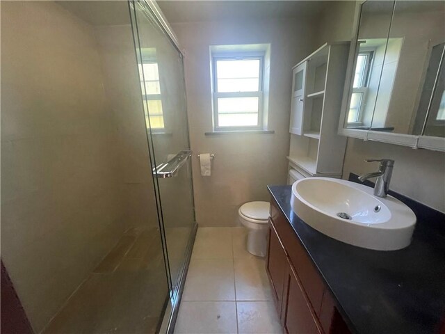 bathroom with tile patterned flooring, vanity, toilet, and walk in shower