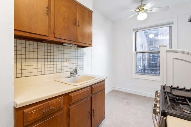 kitchen with tasteful backsplash, ceiling fan, sink, and gas stove