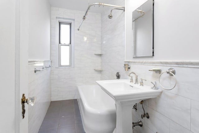 bathroom with tiled shower / bath combo, tile patterned floors, and tile walls