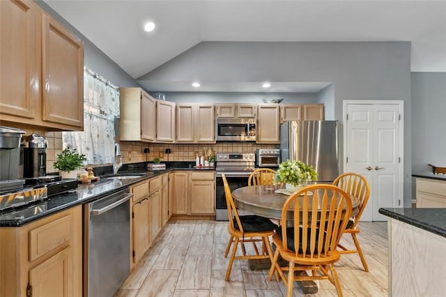 kitchen featuring stainless steel appliances, lofted ceiling, a sink, and light brown cabinetry