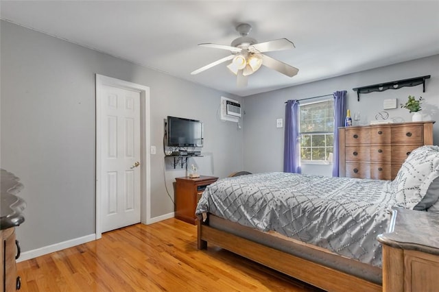 bedroom with a ceiling fan, baseboards, light wood finished floors, and a wall mounted AC