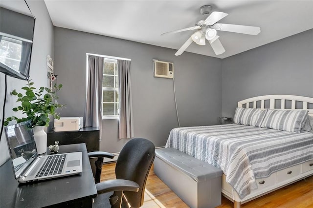 bedroom featuring ceiling fan, a wall unit AC, and light wood-style flooring