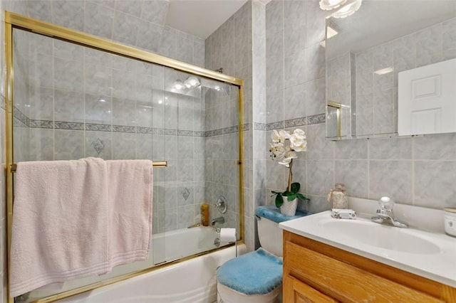 bathroom with toilet, enclosed tub / shower combo, tile walls, and vanity