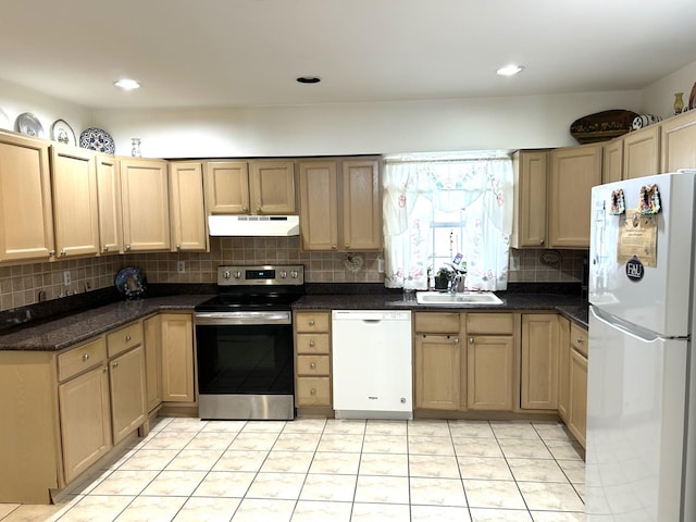 kitchen featuring under cabinet range hood, white appliances, a sink, tasteful backsplash, and dark stone countertops