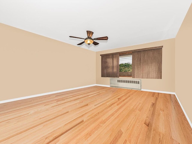 spare room featuring ceiling fan, light hardwood / wood-style floors, and radiator heating unit