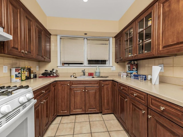 kitchen featuring tasteful backsplash, white gas stove, light tile patterned floors, and sink