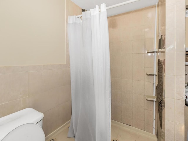 bathroom with toilet, tile walls, and a shower with shower curtain