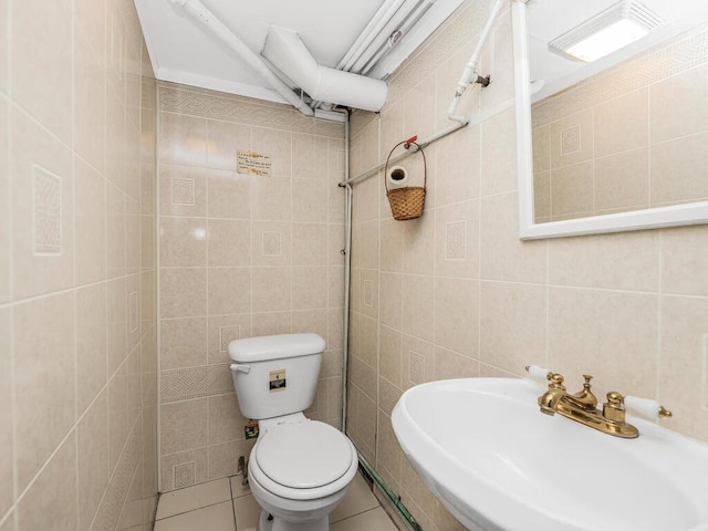 bathroom featuring tile patterned floors, toilet, sink, and tile walls