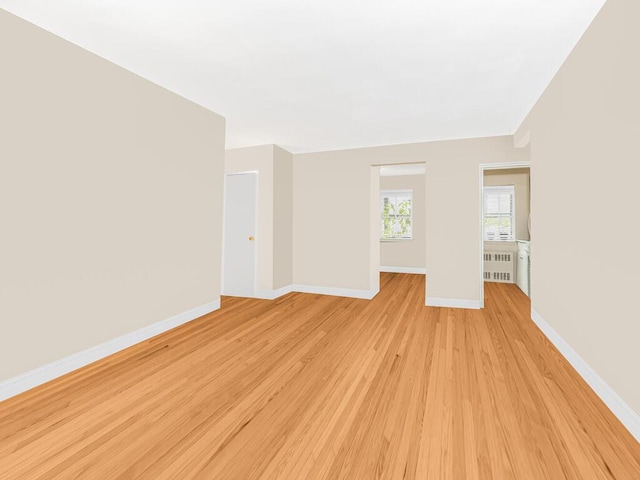 spare room featuring radiator heating unit and light hardwood / wood-style flooring