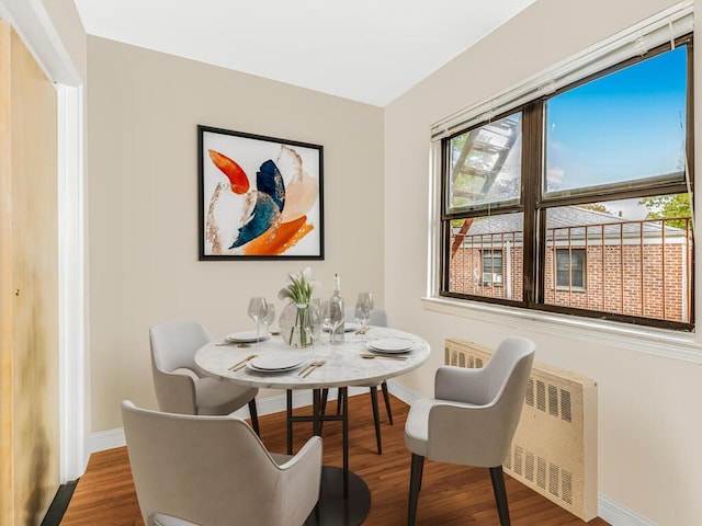 dining space with hardwood / wood-style flooring and radiator