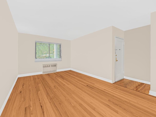 unfurnished room with radiator heating unit and wood-type flooring