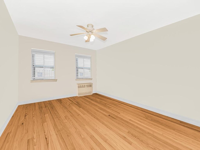 empty room with radiator heating unit, light hardwood / wood-style flooring, and ceiling fan