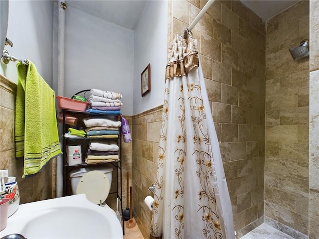 bathroom featuring sink, curtained shower, toilet, and tile walls