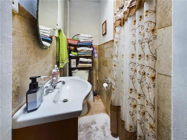 bathroom with walk in shower, tile patterned floors, toilet, vanity, and tile walls