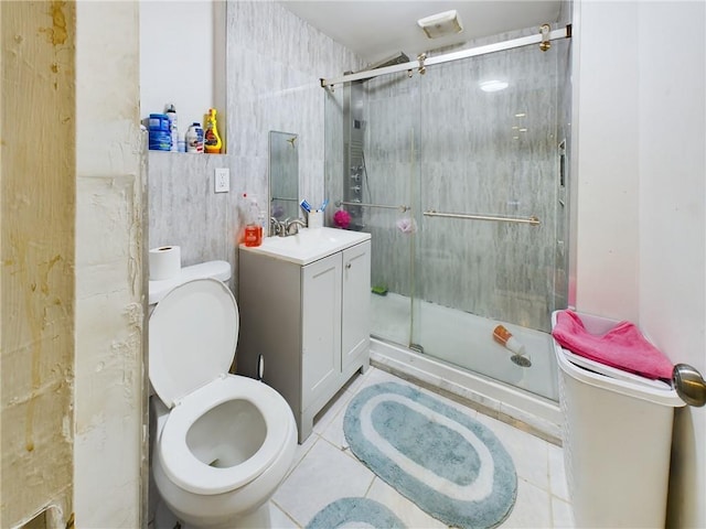 bathroom featuring vanity, tile patterned flooring, toilet, tile walls, and a shower with shower door