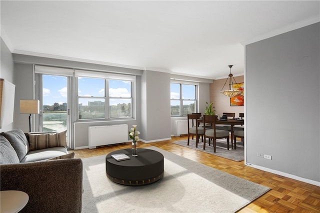 living room with radiator heating unit, parquet flooring, a wealth of natural light, and ornamental molding