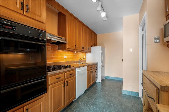 kitchen featuring tasteful backsplash, stainless steel appliances, extractor fan, dark tile patterned floors, and sink