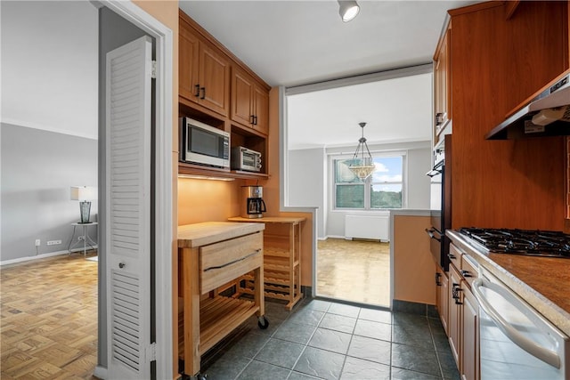 kitchen featuring dark parquet floors, hanging light fixtures, wall chimney range hood, and appliances with stainless steel finishes