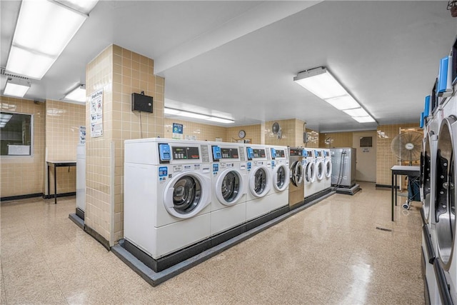 clothes washing area with washer and clothes dryer and tile walls