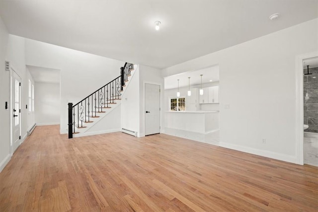 unfurnished living room with light hardwood / wood-style flooring and a baseboard heating unit