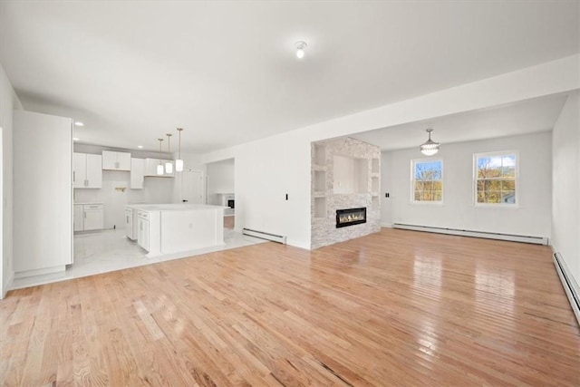 unfurnished living room with a fireplace, light hardwood / wood-style floors, and a baseboard heating unit