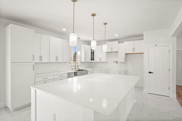 kitchen featuring white cabinets, a center island, sink, and pendant lighting