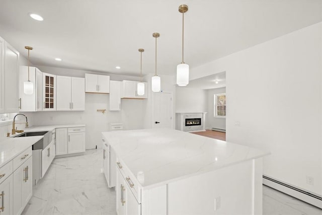 kitchen featuring light stone counters, a baseboard heating unit, sink, white cabinets, and a center island