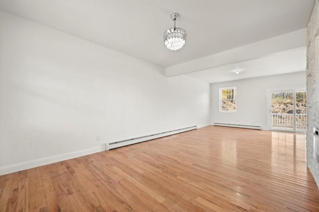 spare room featuring light hardwood / wood-style floors, a notable chandelier, and a baseboard heating unit