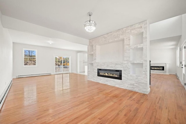 unfurnished living room with a fireplace, an inviting chandelier, a baseboard radiator, and light hardwood / wood-style flooring