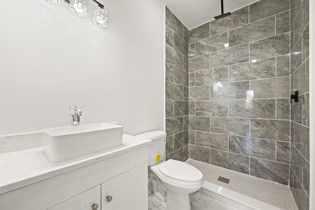 bathroom featuring a tile shower, vanity, and toilet