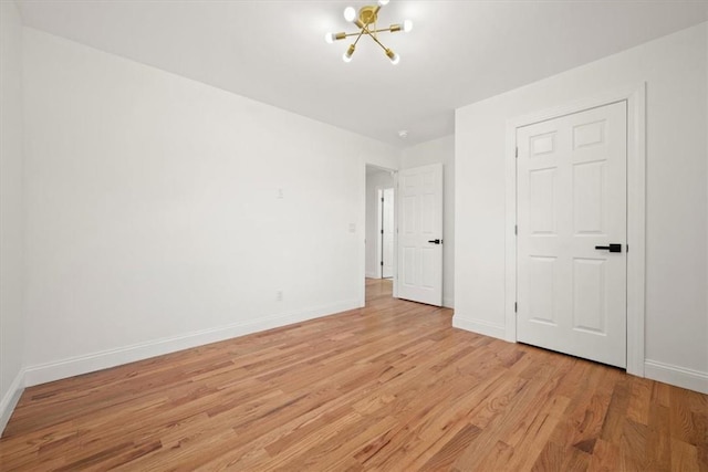 unfurnished bedroom with a chandelier, a closet, and light hardwood / wood-style flooring