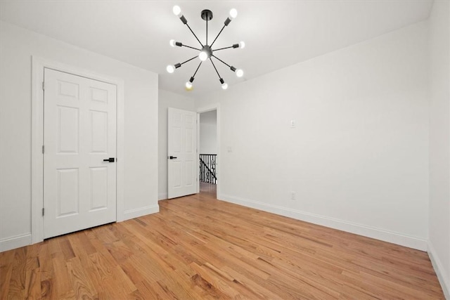 unfurnished bedroom with an inviting chandelier and light wood-type flooring