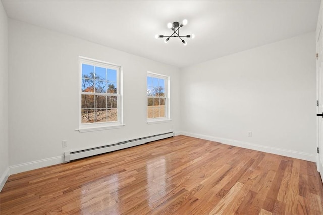 spare room featuring an inviting chandelier, light hardwood / wood-style flooring, and a baseboard radiator