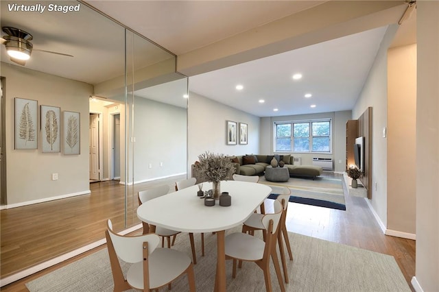 dining room with light wood-type flooring, a wall unit AC, and ceiling fan