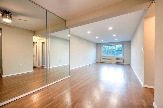 unfurnished living room featuring radiator, ceiling fan, and wood-type flooring