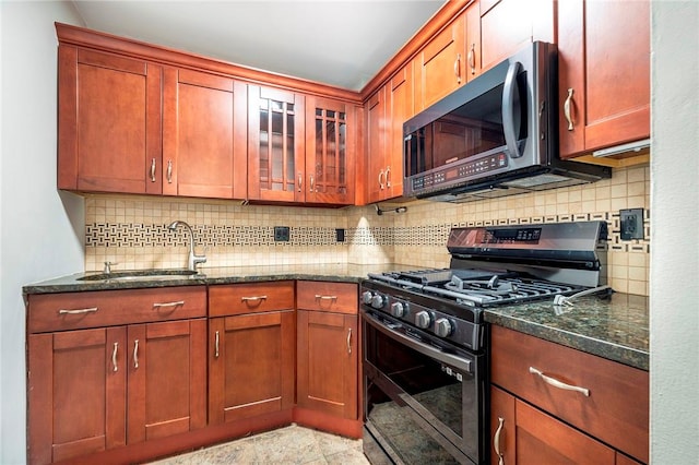 kitchen with tasteful backsplash, sink, appliances with stainless steel finishes, and dark stone counters