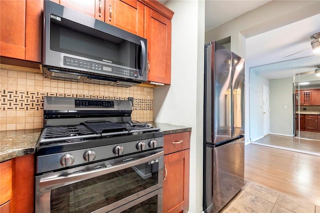 kitchen with dark stone countertops, decorative backsplash, light hardwood / wood-style flooring, and appliances with stainless steel finishes