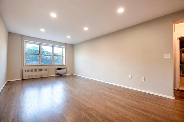 spare room featuring a wall mounted air conditioner, dark hardwood / wood-style flooring, and radiator