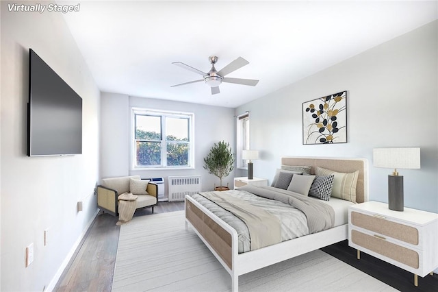 bedroom featuring radiator heating unit, ceiling fan, and hardwood / wood-style floors