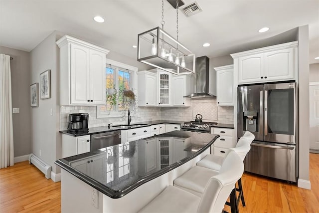 kitchen with sink, hanging light fixtures, wall chimney exhaust hood, appliances with stainless steel finishes, and a kitchen island