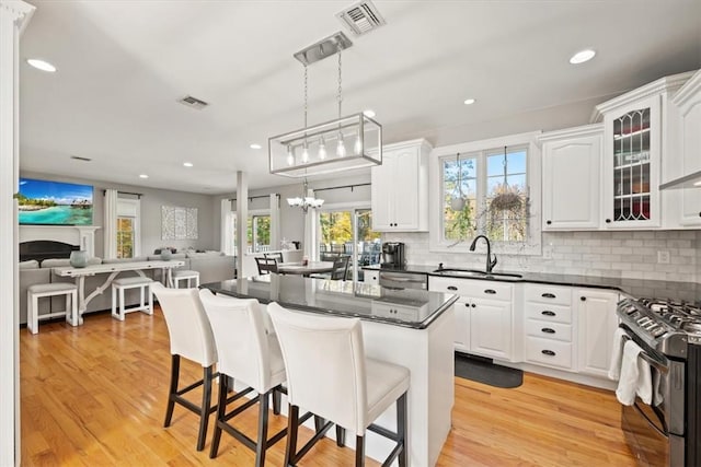 kitchen with plenty of natural light, pendant lighting, light hardwood / wood-style floors, white cabinets, and appliances with stainless steel finishes