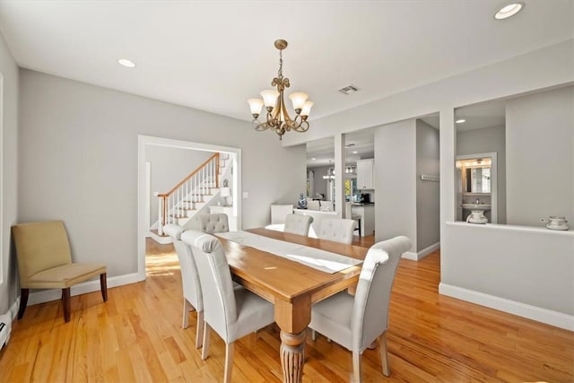 dining area featuring light wood-type flooring, baseboard heating, and a chandelier