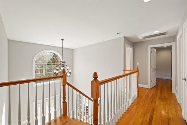 hall with light wood-type flooring and a notable chandelier