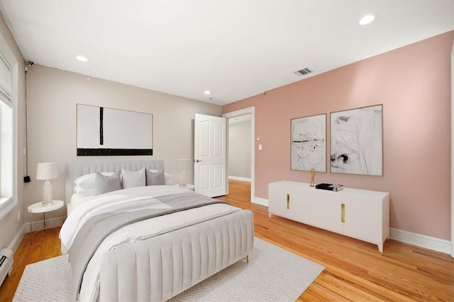 bedroom with light hardwood / wood-style floors and a baseboard radiator