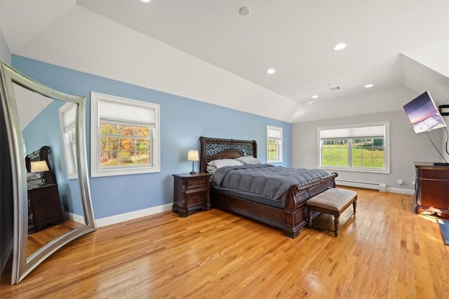 bedroom with light hardwood / wood-style floors, vaulted ceiling, and a baseboard heating unit